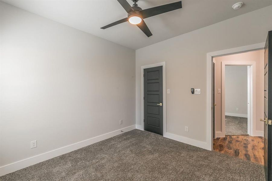 Unfurnished bedroom featuring ceiling fan and dark carpet