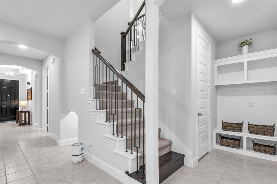 Stairway featuring arched walkways, baseboards, a chandelier, and tile patterned floors