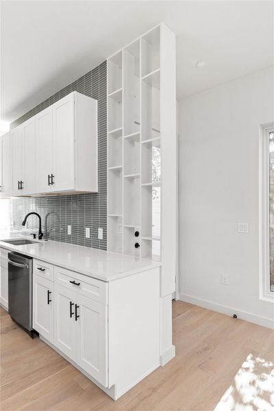 Kitchen featuring open shelves, white cabinets, tasteful backsplash, light wood-type flooring, and light stone countertops