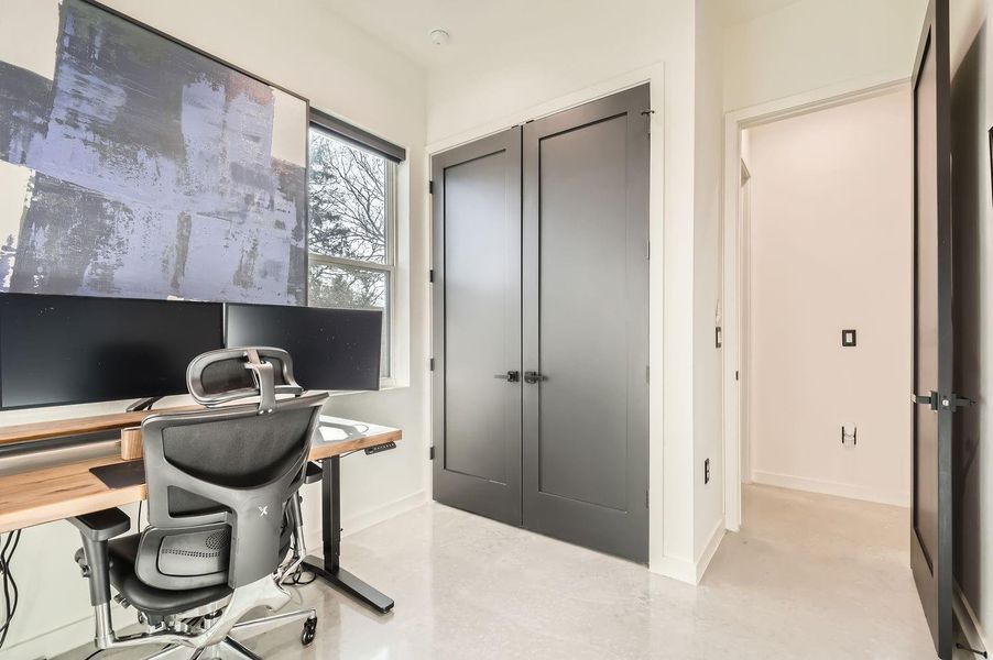 Concrete flooring in the secondary bedroom mirrors the main living areas, creating a sleek, cohesive design throughout.