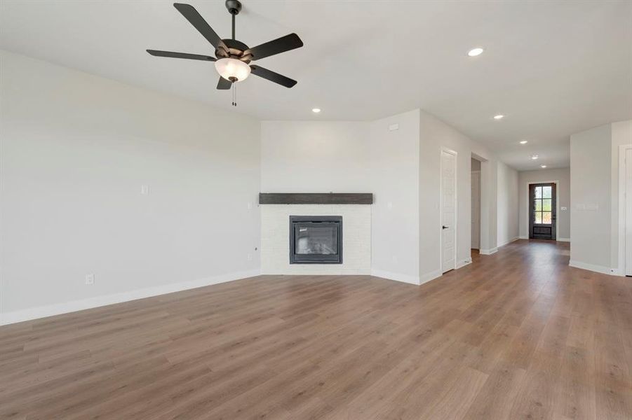 Unfurnished living room featuring a glass covered fireplace, recessed lighting, a ceiling fan, and dark wood-style flooring