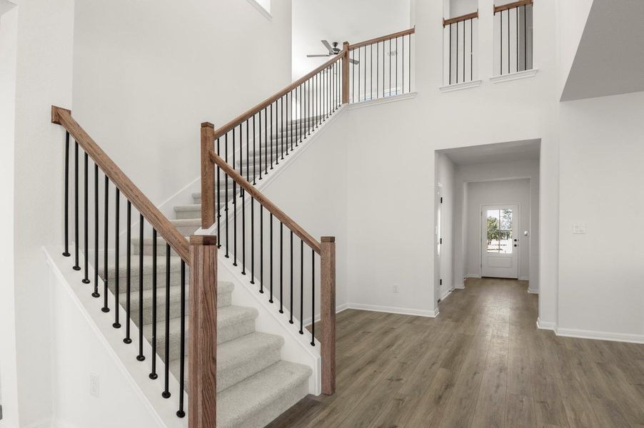 Staircase featuring a high ceiling, wood finished floors, and ceiling fan