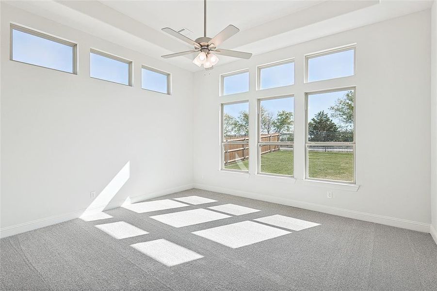 Unfurnished room with a towering ceiling, carpet floors, and ceiling fan