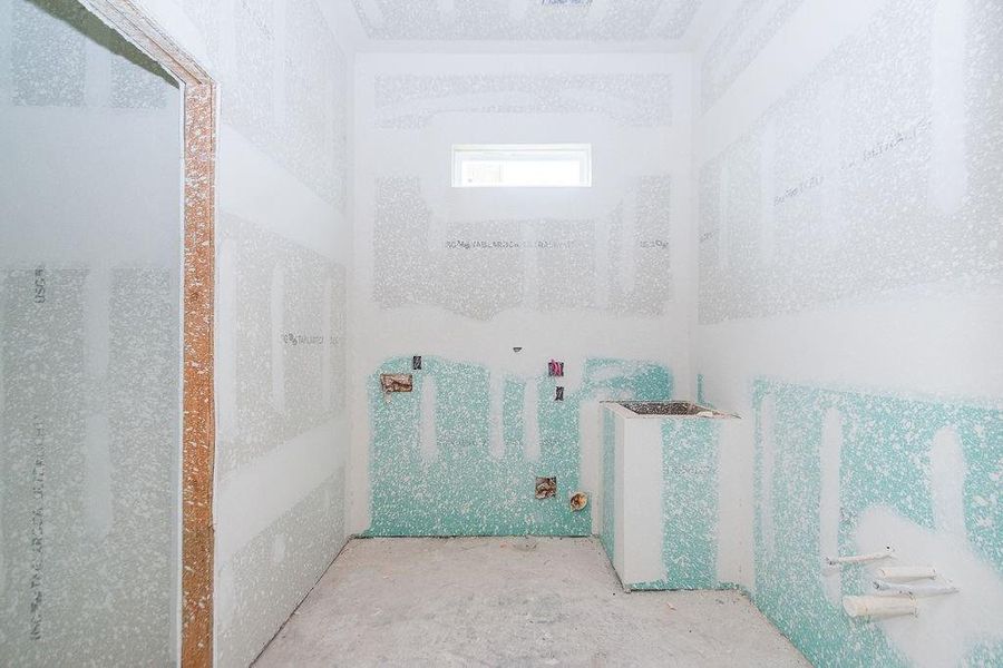 Unfinished utility room with drywall installed, featuring plumbing and electrical setups ready for completion. Unfinished utility room with drywall installed, featuring plumbing and electrical setups ready for completion.