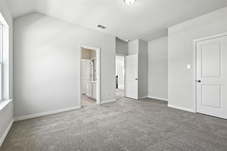 Unfurnished bedroom with light colored carpet and ensuite bathroom
