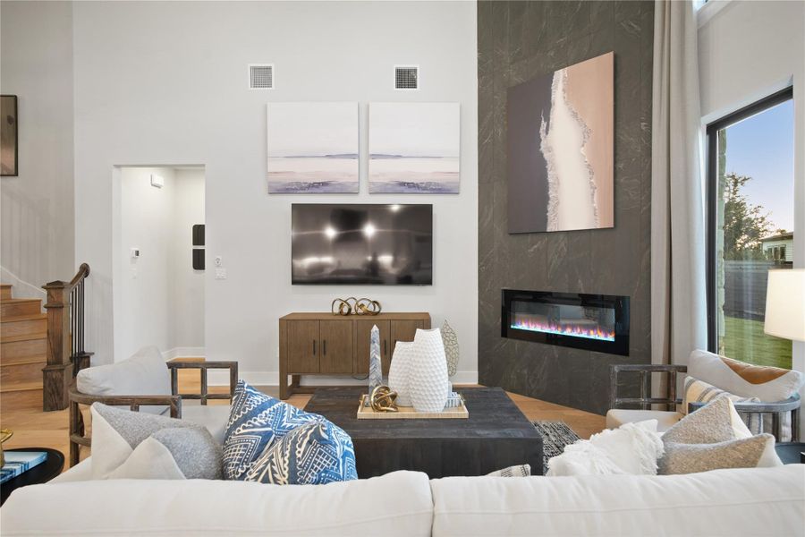 Living area featuring a high end fireplace, stairway, a towering ceiling, and wood finished floors