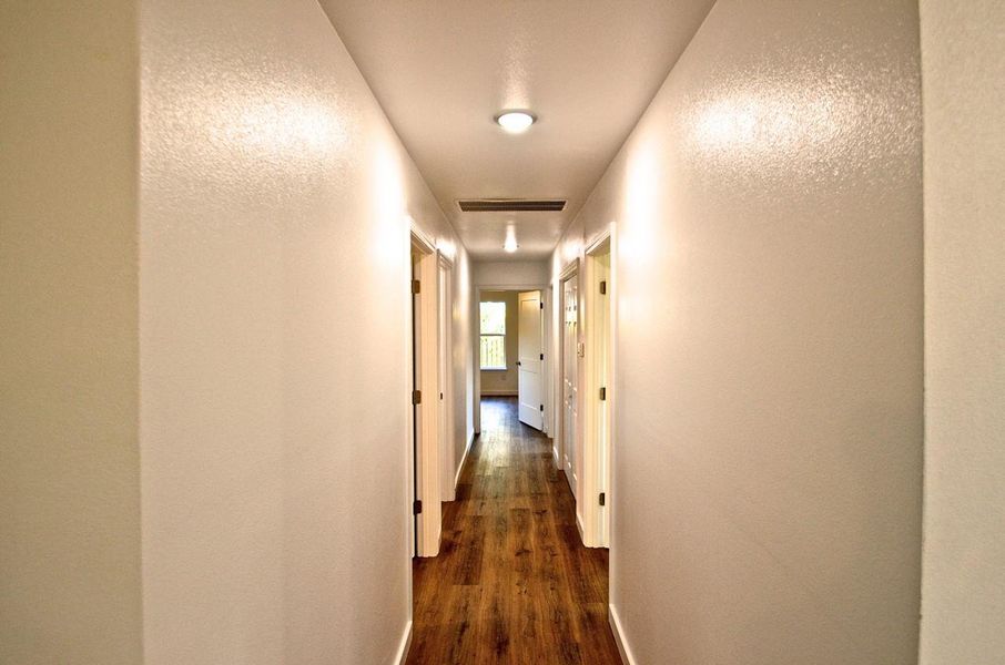 Hallway with a textured wall and dark wood-style floors