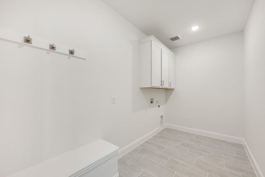 Laundry room with white upper cabinets, wall hooks, washer hookup, and light tile floors Laundry room with white upper cabinets, wall hooks, washer hookup, and light tile floors
