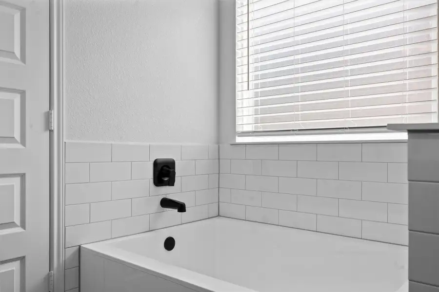 Bathroom featuring a bath and a textured wall
