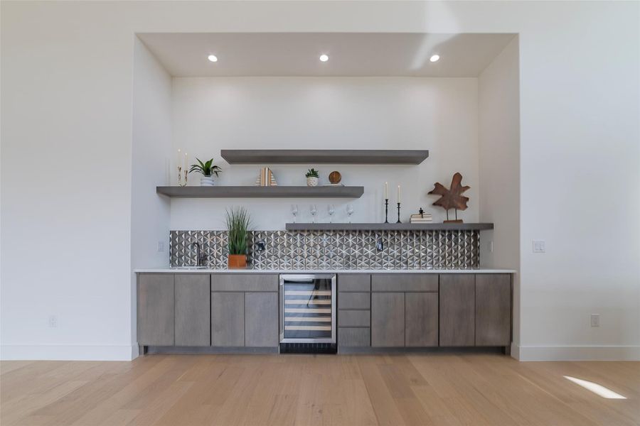Indoor dry bar featuring wine cooler, open shelves, light wood-style flooring, modern cabinets, and recessed lighting