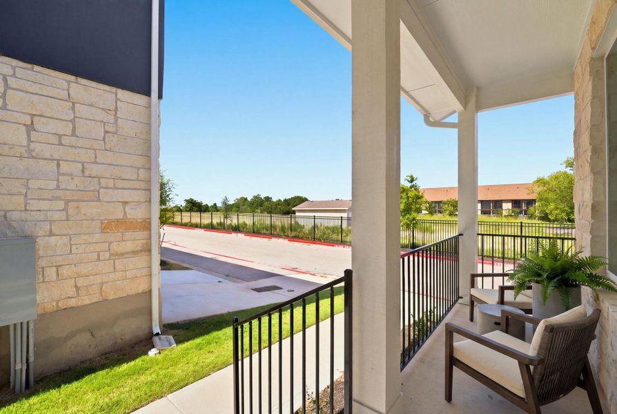 A sheltered concrete porch displays elegant stone masonry and classic metal railings.