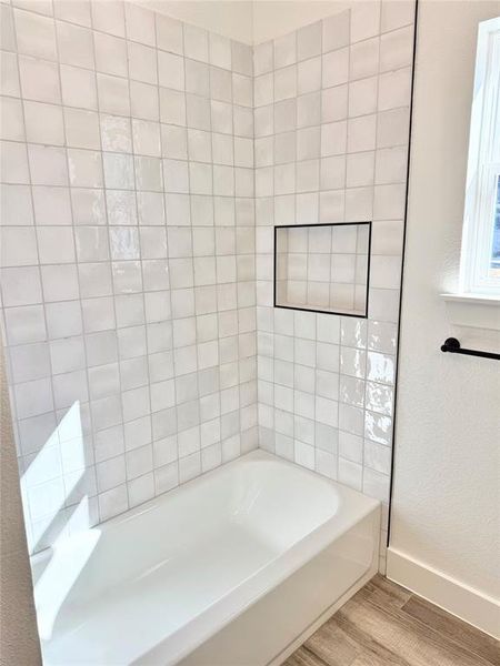 Full bathroom featuring a bath, baseboards, and wood finished floors