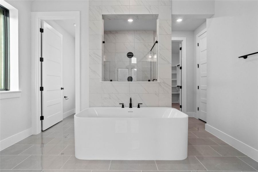 The centerpiece of this contemporary primary bath is the deep, freestanding bathtub, offering an ideal spot for relaxation with a unique view into the walk-in shower.
