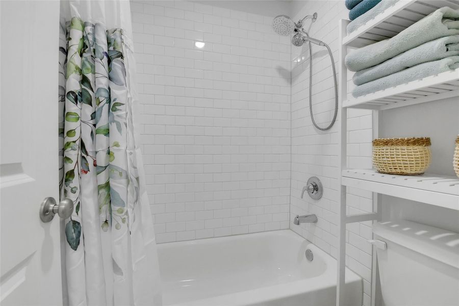 Upstairs secondary bathroom tub/shower with tile surround.