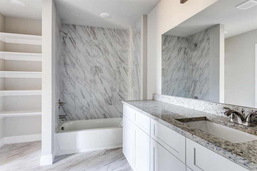 Full bath with a combined bath / shower with marble appearance, light marble finish floors, and vanity