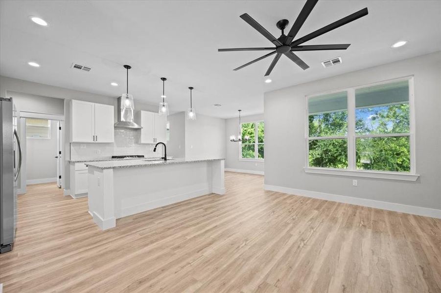 Kitchen with wall chimney range hood, white cabinets, light wood finished floors, tasteful backsplash, and recessed lighting