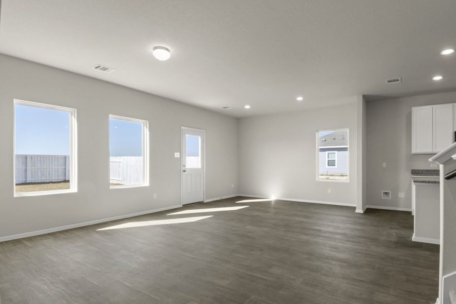Image of a living room with cream walls, windows, a back door, dark brown flooring and white trim Image of a living room with cream walls, windows, a back door, dark brown flooring and white trim