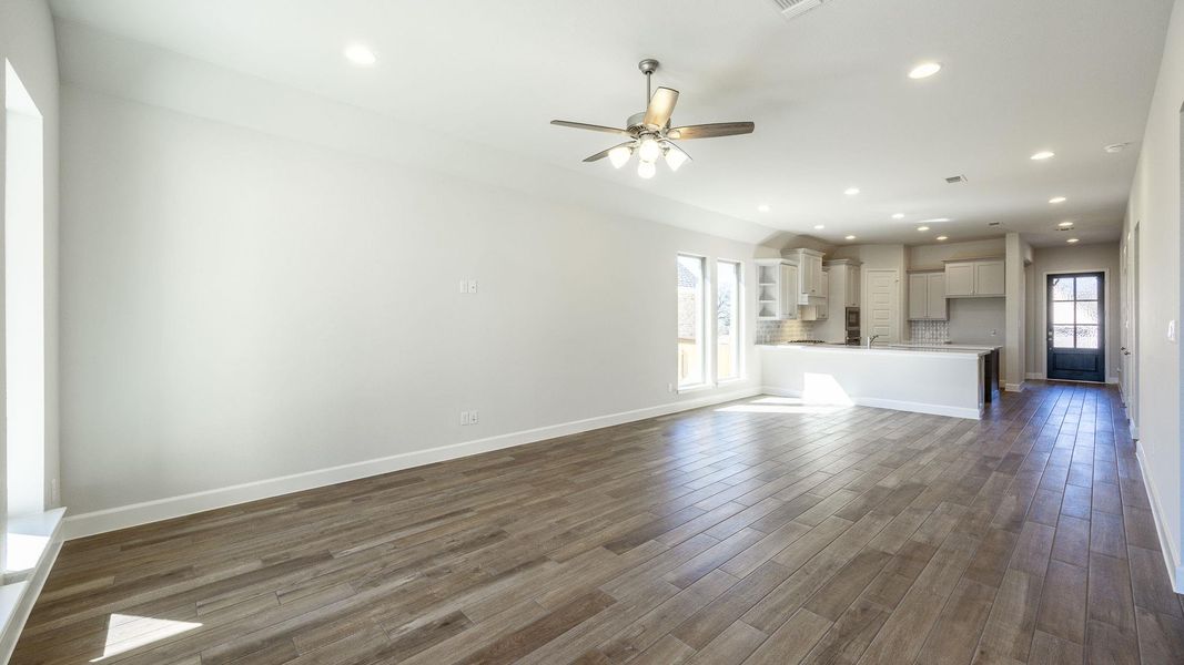 Unfurnished living room featuring visible vents, baseboards, recessed lighting, ceiling fan, and dark wood-type flooring