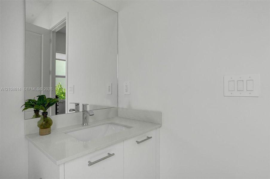 White vanity with an integrated rectangular sink, chrome faucet, and full-width mirror