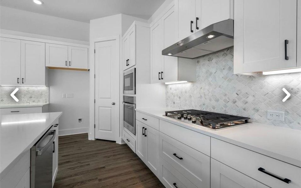 Kitchen with white cabinetry, stainless steel appliances, dark wood-style floors, light stone countertops, and recessed lighting