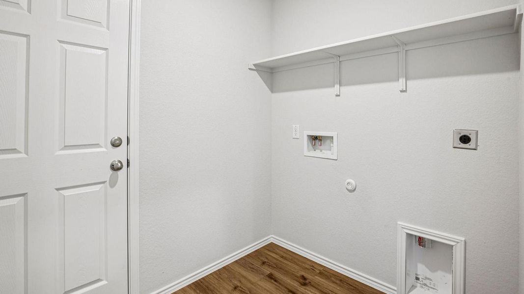 Dedicated laundry area featuring wood-finish flooring, white walls, and a built-in white shelf Dedicated laundry area featuring wood-finish flooring, white walls, and a built-in white shelf