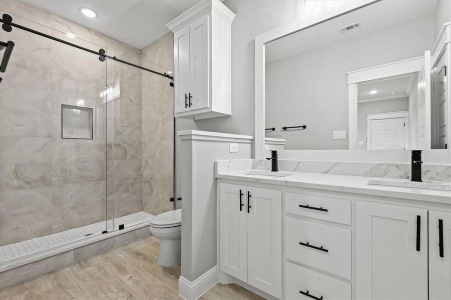 Bathroom featuring an enclosed shower, hardwood / wood-style floors, toilet, and vanity