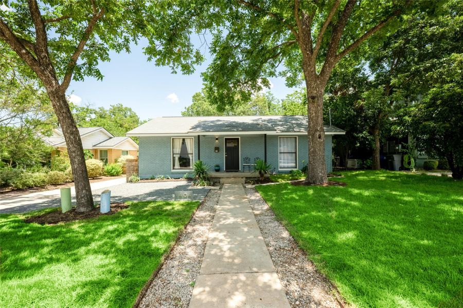 A welcoming light blue brick home with a verdant lawn and mature shade trees. A welcoming light blue brick home with a verdant lawn and mature shade trees.