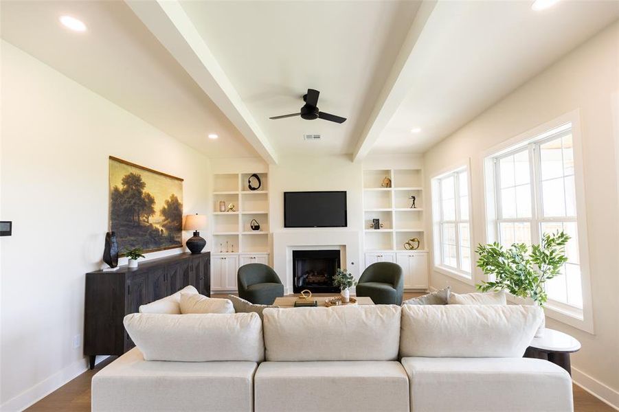 Living area featuring a fireplace with a mantel, built-in shelving, recessed lighting, and a ceiling fan