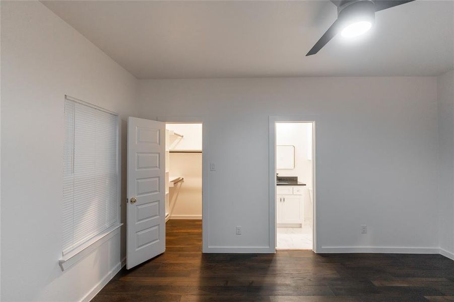 Unfurnished bedroom featuring ensuite bathroom, dark wood-style floors, a closet, baseboards, and a spacious closet Unfurnished bedroom featuring ensuite bathroom, dark wood-style floors, a closet, baseboards, and a spacious closet