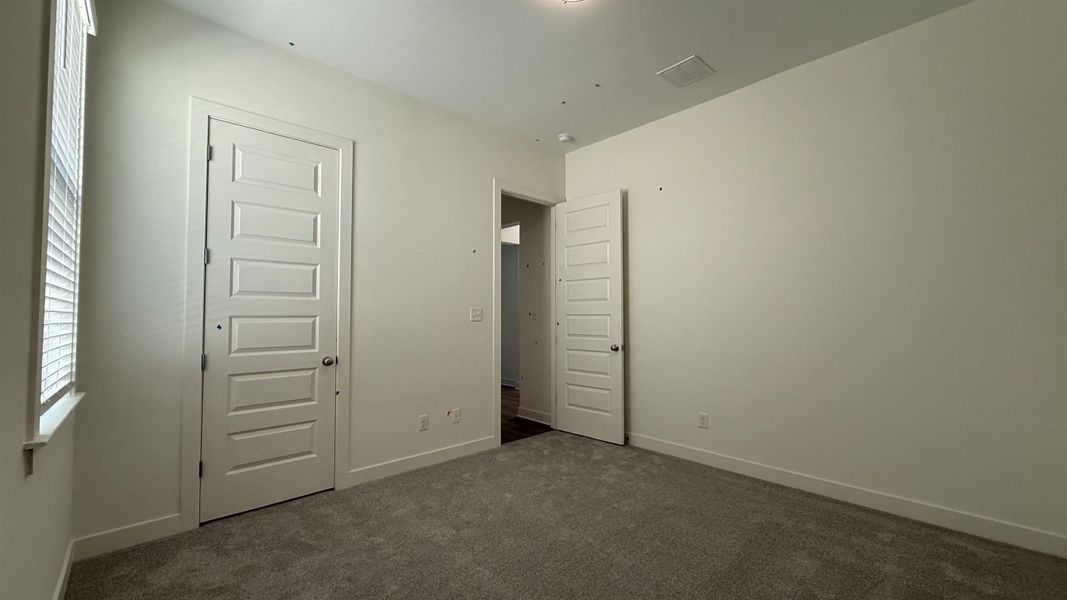 Unfurnished bedroom with dark colored carpet and baseboards