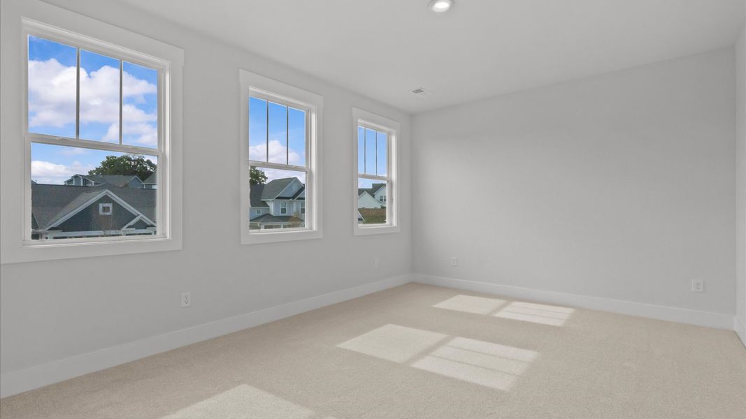 Elegant bedroom retreat featuring soft carpet and oversized windows that create a bright, welcoming space