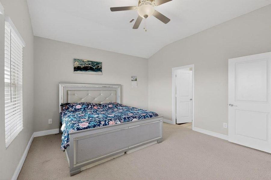 Bedroom featuring light carpet, vaulted ceiling, and ceiling fan Bedroom featuring light carpet, vaulted ceiling, and ceiling fan