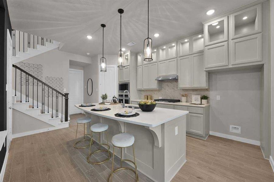 Quartz countertops, pendant lighting, and upgraded cabinetry.  (Original Builder Staged Photo 2024)
