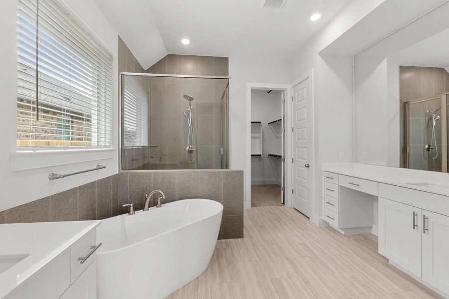 Bathroom featuring a stall shower, vanity, a freestanding tub, a spacious closet, and recessed lighting Bathroom featuring a stall shower, vanity, a freestanding tub, a spacious closet, and recessed lighting