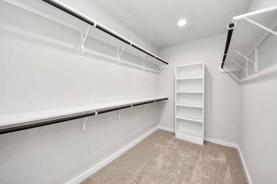Walk-in closet that epitomizes luxury and practicality. This generously sized space features built-in shelving, offering abundant room for impeccable organization. High ceilings and recessed lighting create a bright and welcoming ambiance. Sample photo of completed home with similar floor plan. Actual colors and selections may vary.