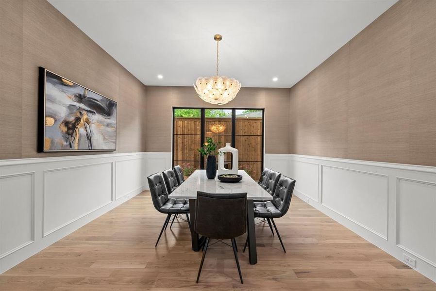 This dining area features light hardwood flooring, wainscoting, and textured wall coverings