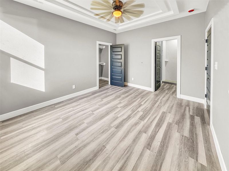Primary bedroom with tray ceiling and ceiling fan