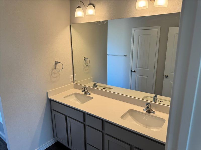 Bathroom with a textured wall and double vanity
