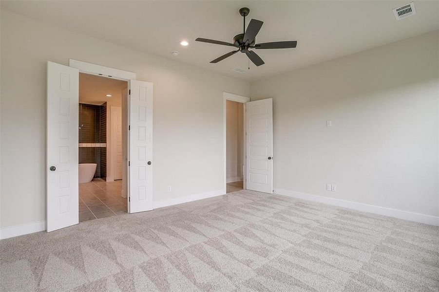 Unfurnished bedroom featuring ceiling fan, connected bathroom, and light carpet