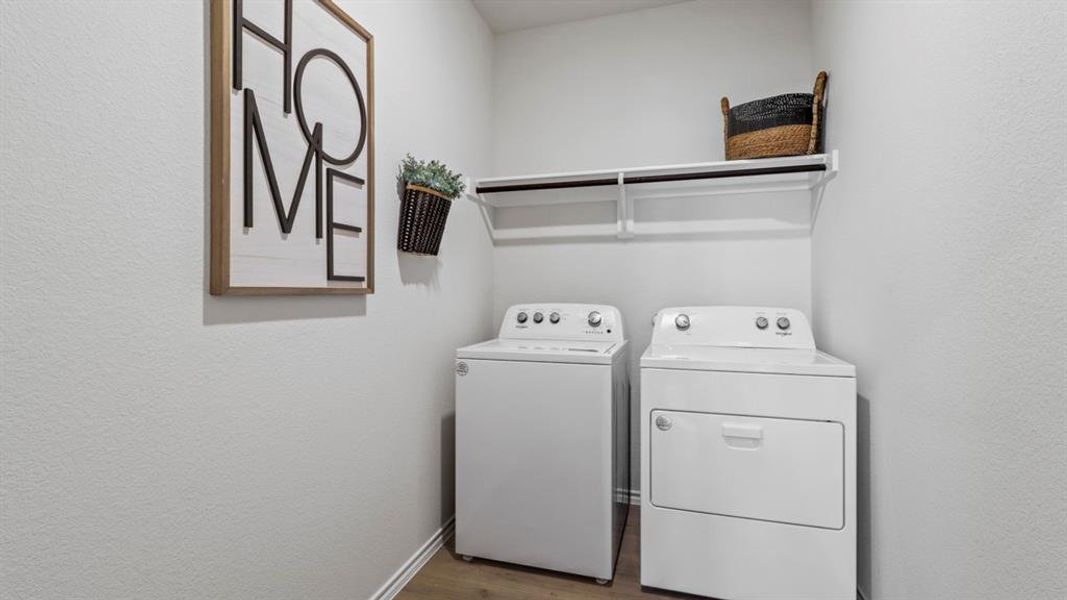 Washroom with dark wood-style flooring, washer and clothes dryer, and a textured wall