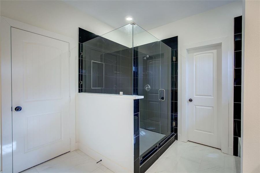 Bathroom featuring a stall shower and light marble finish flooring Bathroom featuring a stall shower and light marble finish flooring