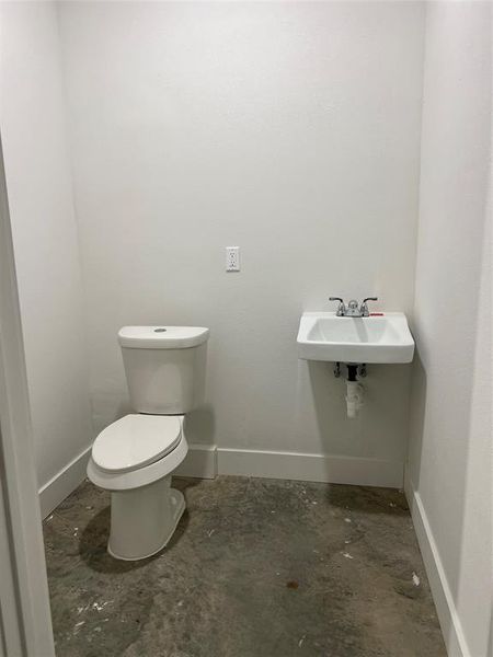 Bathroom featuring concrete flooring, toilet, and sink