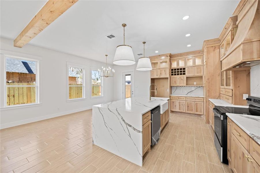 Kitchen featuring black electric range oven, light stone countertops, light wood finish cabinets, a kitchen island with sink, and decorative backsplash Kitchen featuring black electric range oven, light stone countertops, light wood finish cabinets, a kitchen island with sink, and decorative backsplash