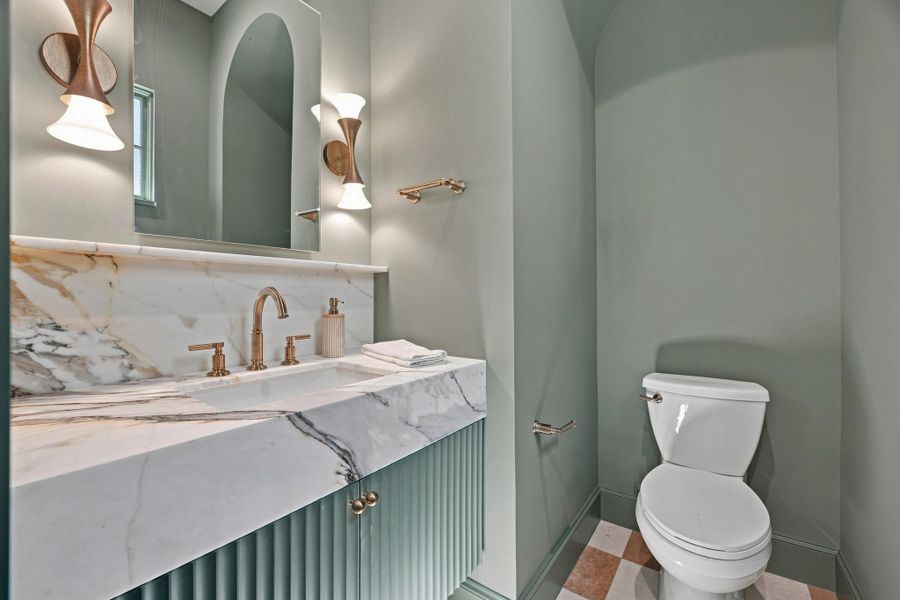 Veined stone counters pair elegantly with a fluted vanity and custom wall fixtures.