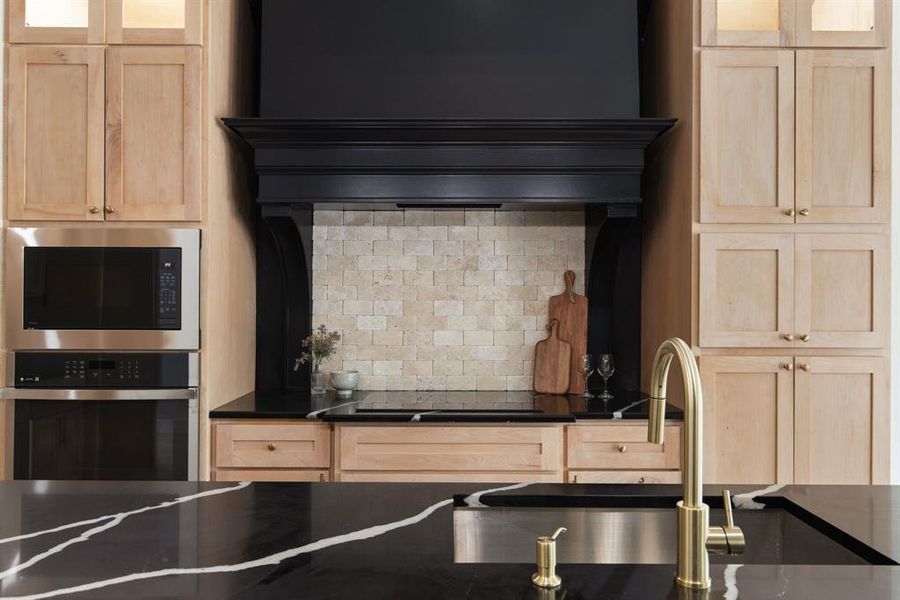 Kitchen with stainless steel appliances, sink, backsplash, and light brown cabinetry