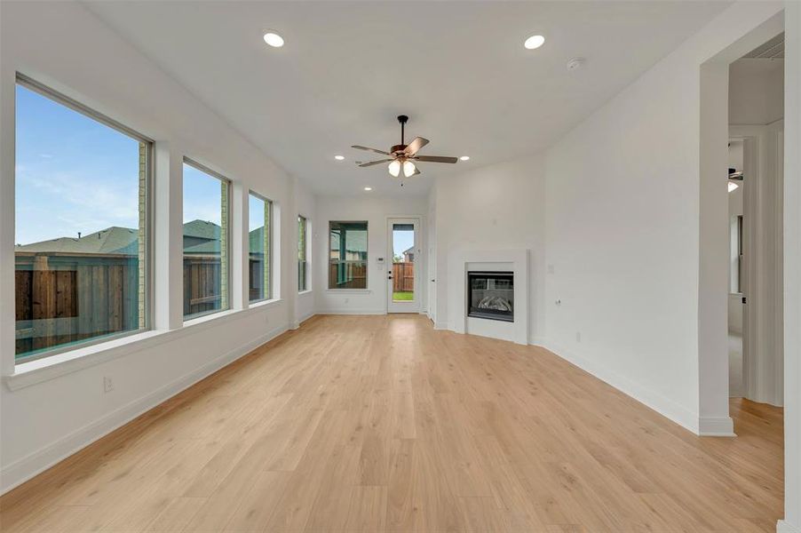 Spacious living area featuring expansive windows, wood-finish flooring, recessed lighting, and a modern fireplace with a white surround