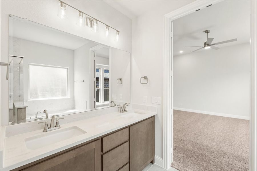 Bathroom with double sink vanity, dark wood cabinets, white countertop, and large mirror with overhead lighting
