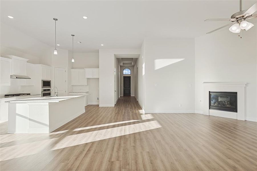 Kitchen featuring a large island with sink, white cabinetry, stainless steel appliances, and light hardwood / wood-style floors