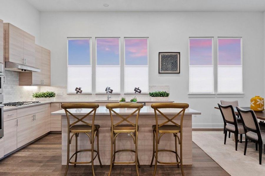 Kitchen with light brown cabinetry, a kitchen bar, tasteful backsplash, and dark wood finished floors