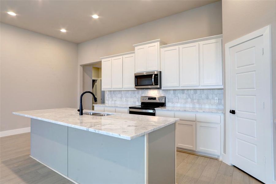 Kitchen featuring white cabinetry, appliances with stainless steel finishes, sink, and a kitchen island with sink